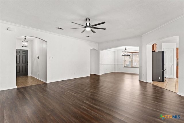 unfurnished living room with visible vents, arched walkways, and wood finished floors