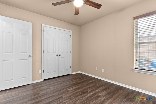 unfurnished bedroom with dark wood-style floors, a closet, ceiling fan, and baseboards