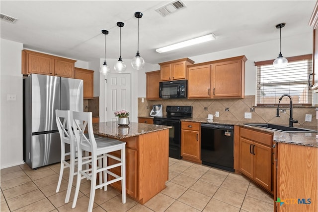 kitchen with visible vents, dark stone counters, a center island, black appliances, and a sink