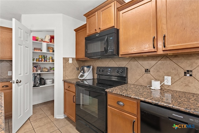 kitchen featuring dark stone counters, black appliances, light tile patterned floors, and decorative backsplash