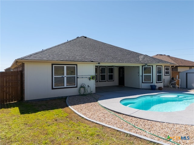 rear view of house featuring an outbuilding, a shingled roof, a storage shed, a patio area, and fence