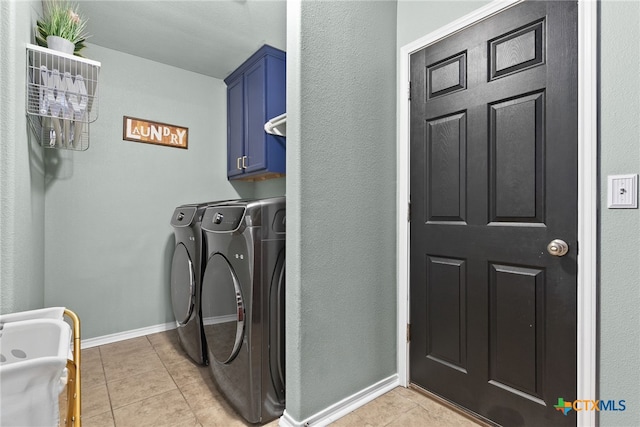 clothes washing area featuring cabinet space, washing machine and dryer, baseboards, and light tile patterned flooring