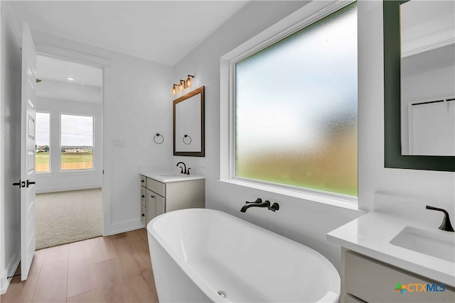 4018 Prairie Dr, Nolanville, TX 76559 - bathroom featuring two vanities, a freestanding bath, wood finished floors, and recessed lighting