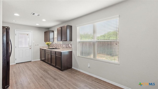 9741 Sandy Ridge Way, San Antonio, TX 78239 - kitchen with freestanding refrigerator, dark brown cabinetry, light countertops, light wood-style floors, and recessed lighting