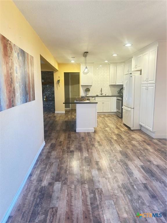 kitchen featuring white fridge, dark hardwood / wood-style flooring, hanging light fixtures, white cabinets, and sink