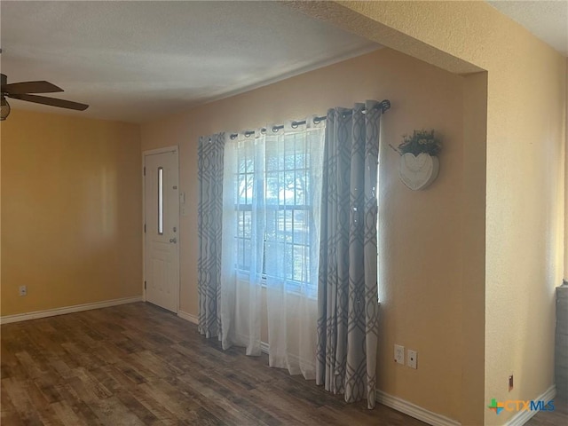 empty room with ceiling fan and dark hardwood / wood-style flooring