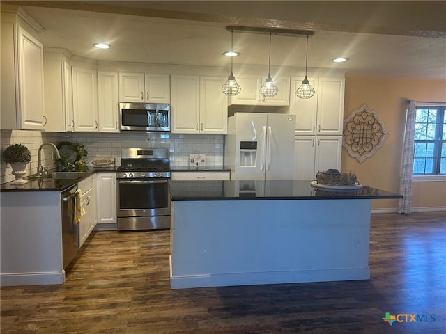 kitchen with appliances with stainless steel finishes, white cabinetry, decorative backsplash, sink, and hanging light fixtures