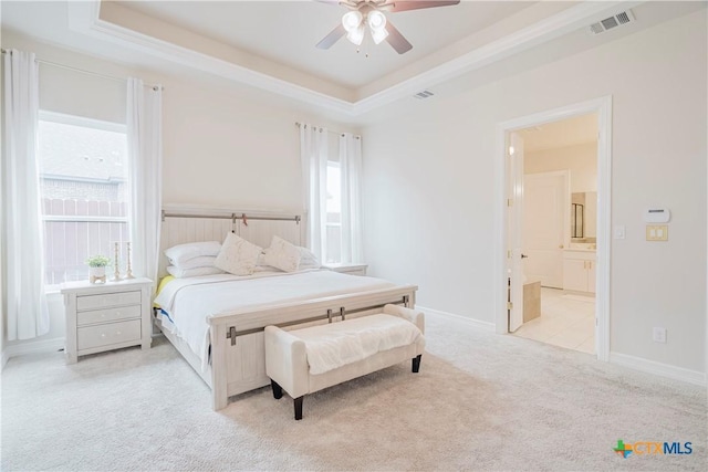 carpeted bedroom with connected bathroom, a tray ceiling, and ceiling fan