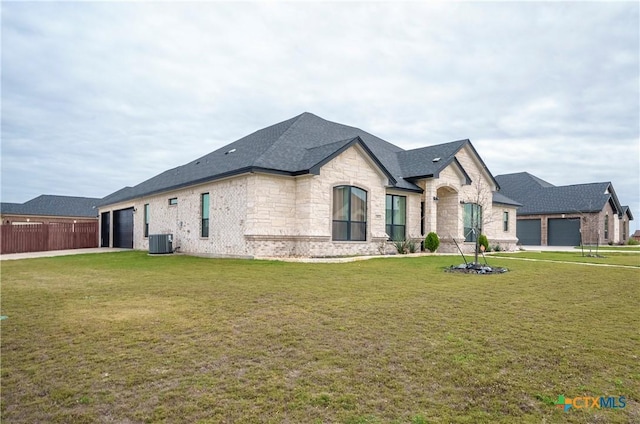 french country style house with a garage, a front lawn, and central air condition unit