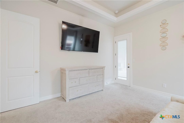 unfurnished bedroom with light colored carpet and a raised ceiling