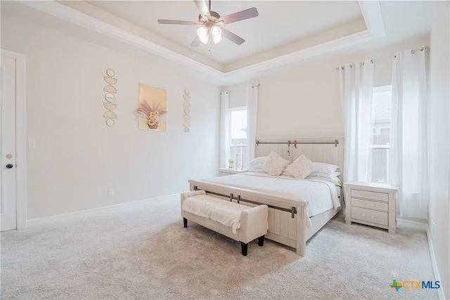 carpeted bedroom featuring a raised ceiling and ceiling fan