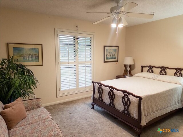 bedroom featuring carpet flooring, multiple windows, baseboards, a textured ceiling, and a ceiling fan