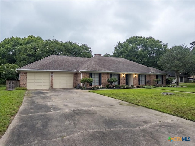 ranch-style home with brick siding, an attached garage, concrete driveway, a front lawn, and a chimney