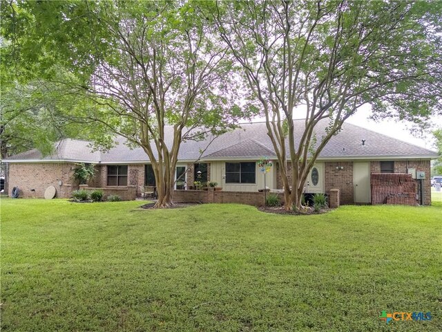 view of front of house featuring brick siding, a front yard, central AC, and roof with shingles