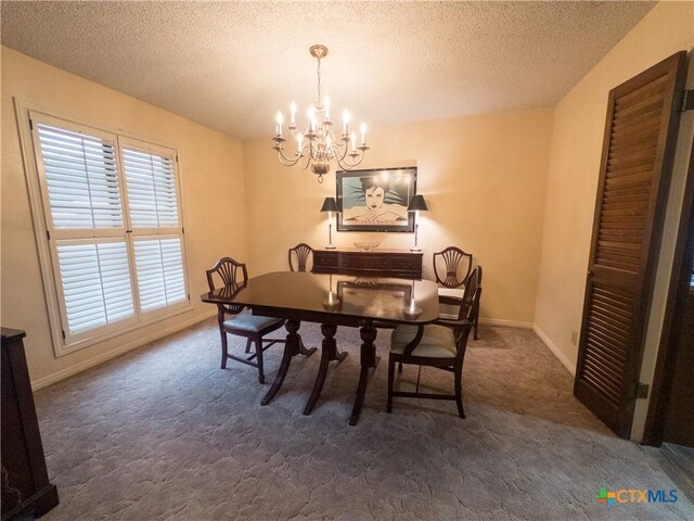 dining room with a chandelier, dark carpet, a textured ceiling, and baseboards