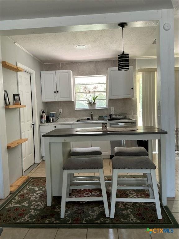 1403 Little St, Copperas Cove, TX 76522 - kitchen with a textured ceiling, white cabinets, a sink, a kitchen breakfast bar, and pendant lighting