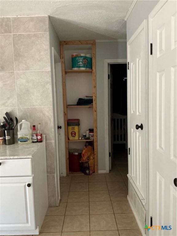 1403 Little St, Copperas Cove, TX 76522 - hallway featuring light tile patterned floors, a textured ceiling, tile walls, and crown molding