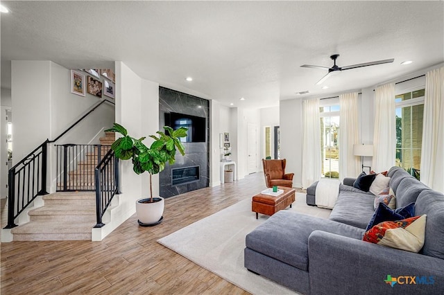 living room with wood finished floors, stairs, a textured ceiling, a fireplace, and recessed lighting