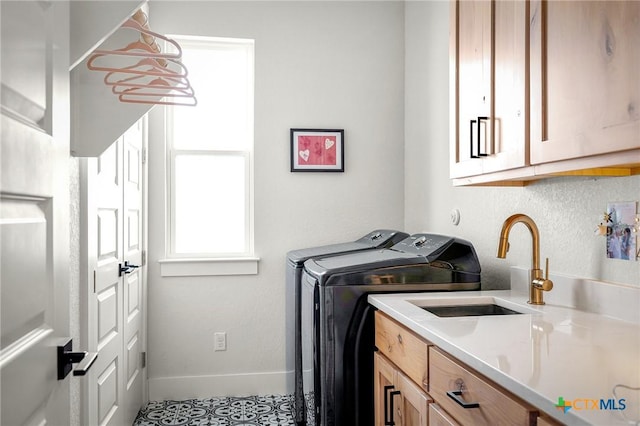 laundry area featuring a sink, washing machine and dryer, cabinet space, and baseboards