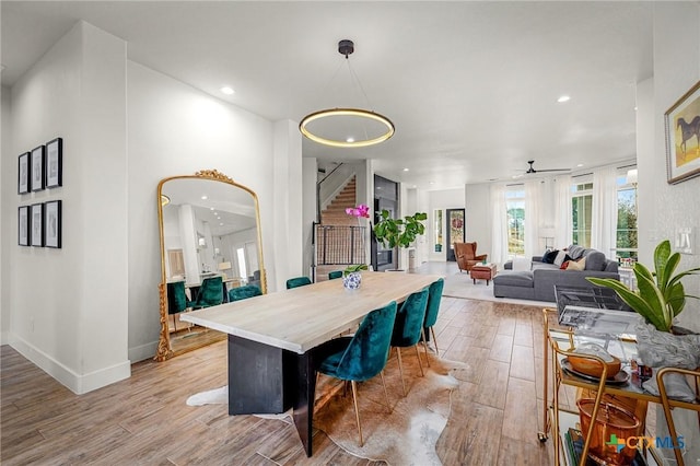 dining space with arched walkways, recessed lighting, baseboards, stairway, and light wood finished floors