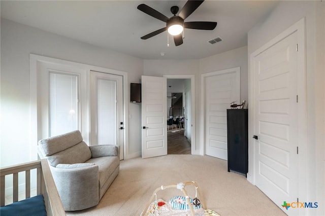 living area featuring light carpet, baseboards, visible vents, and a ceiling fan