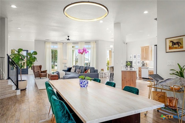 dining area featuring light wood-type flooring, ceiling fan, recessed lighting, and stairs