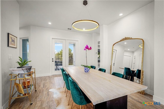 dining space featuring light wood finished floors, baseboards, arched walkways, and recessed lighting