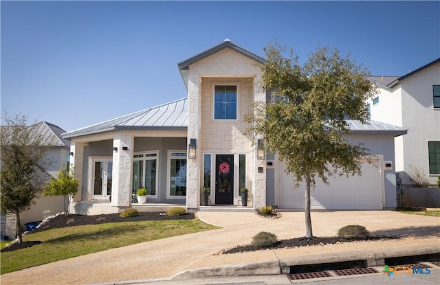 view of front facade with metal roof, concrete driveway, a standing seam roof, and a garage