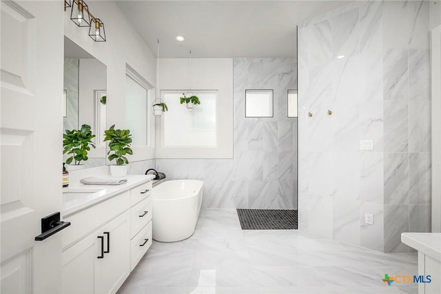 full bath featuring marble finish floor, tile walls, vanity, a walk in shower, and a freestanding tub