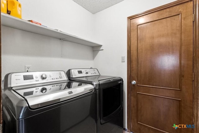 clothes washing area with washing machine and dryer and a textured ceiling