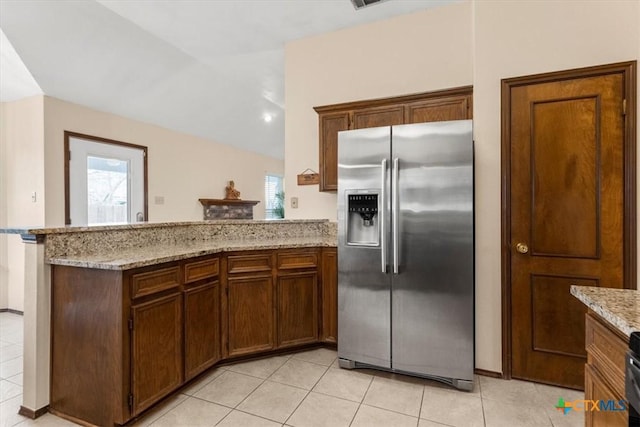 kitchen with light stone counters, lofted ceiling, kitchen peninsula, and stainless steel fridge with ice dispenser