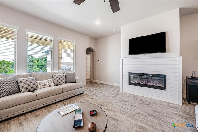 8508 Mount Nebo Cir, Belton, TX 76513 - living area featuring a ceiling fan, a glass covered fireplace, arched walkways, wood finished floors, and recessed lighting
