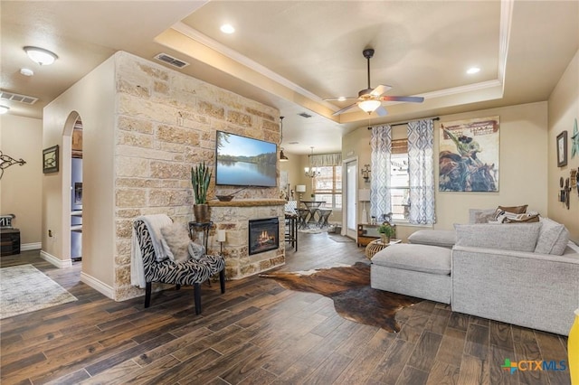 living room with a tray ceiling, arched walkways, visible vents, and wood finished floors