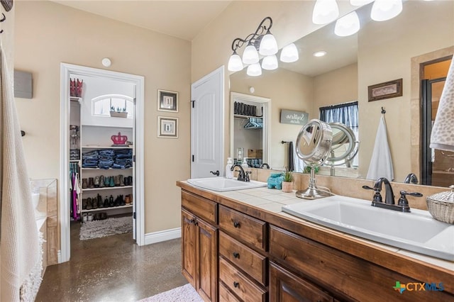 full bath featuring a sink, a spacious closet, finished concrete floors, and double vanity