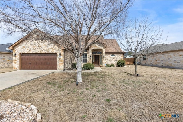 view of front of house with an attached garage, a front lawn, fence, stone siding, and driveway