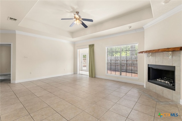 217 Ciela Vis, Seguin, TX 78155 - unfurnished living room featuring ornamental molding, ceiling fan, a raised ceiling, a tiled fireplace, and light tile patterned floors