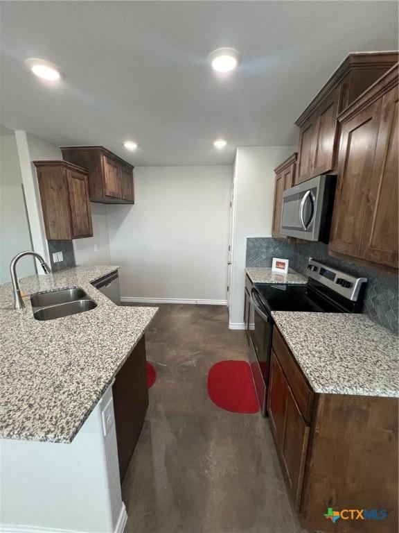 kitchen with tasteful backsplash, baseboards, light stone countertops, appliances with stainless steel finishes, and a sink