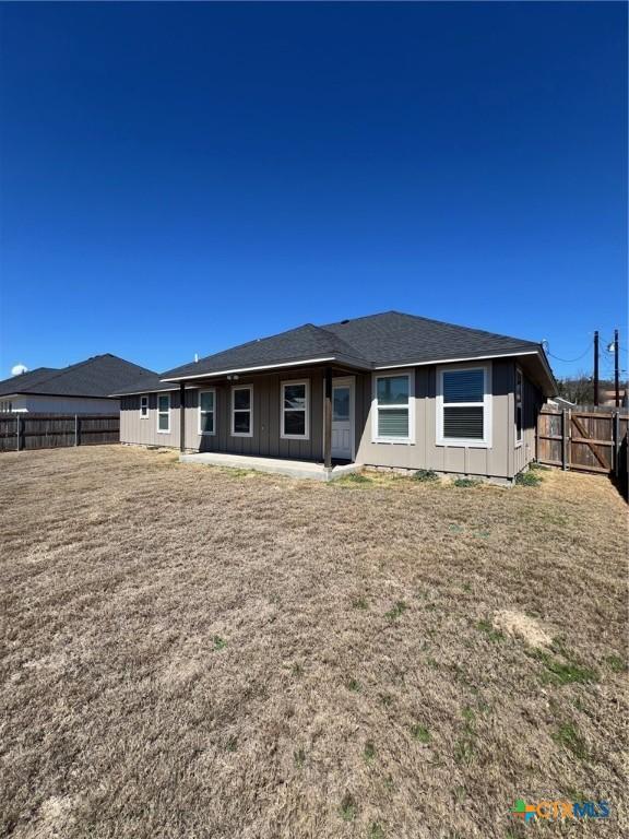 back of property with a fenced backyard and roof with shingles