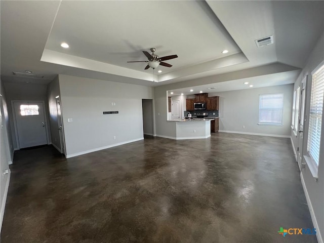 unfurnished living room with baseboards, concrete floors, visible vents, recessed lighting, and a raised ceiling