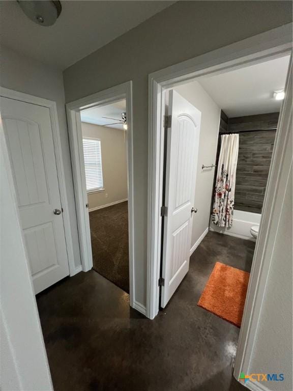 hallway featuring baseboards and concrete floors