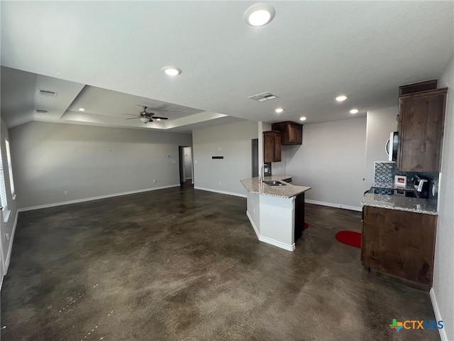 kitchen with a sink, stainless steel microwave, recessed lighting, concrete floors, and baseboards