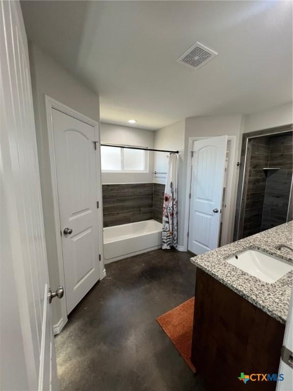 full bathroom with vanity, visible vents, concrete flooring, and tiled shower / bath combo