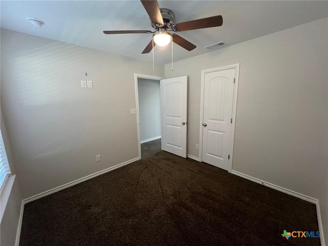 unfurnished bedroom featuring dark colored carpet, visible vents, baseboards, and a ceiling fan