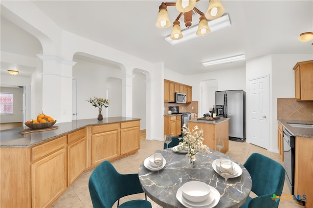 dining area featuring light tile patterned floors, ornate columns, and sink