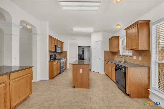 kitchen with black appliances, sink, decorative backsplash, ornate columns, and a kitchen island