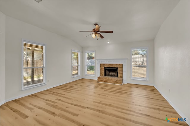 unfurnished living room with a stone fireplace, ceiling fan, light hardwood / wood-style floors, and vaulted ceiling