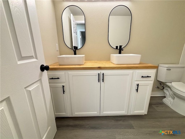 bathroom featuring wood-type flooring, vanity, and toilet