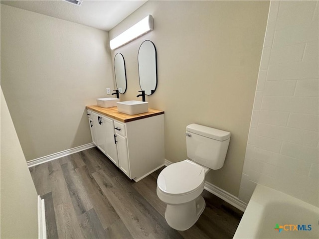 bathroom featuring vanity, toilet, a bathing tub, and hardwood / wood-style floors