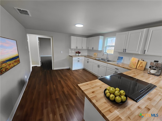 kitchen with butcher block counters, sink, white cabinets, black electric stovetop, and dark wood-type flooring