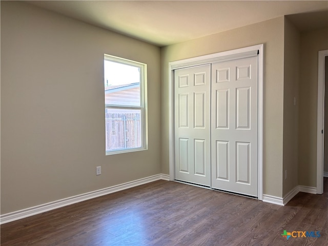 unfurnished bedroom with dark hardwood / wood-style floors and a closet